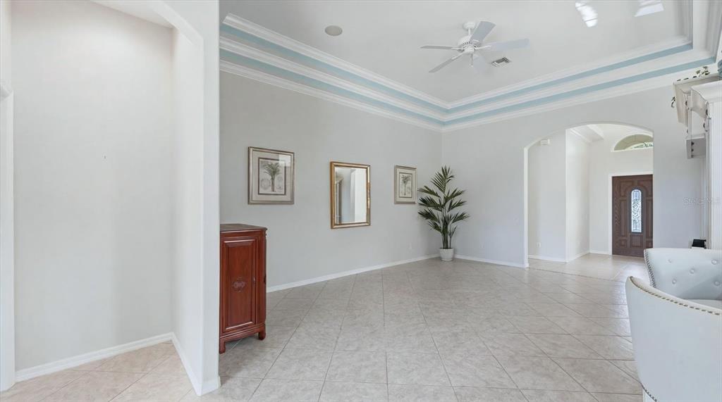 A spacious living area features light tile flooring, a tray ceiling, and a dark wood cabinet — 3337 PINE SHADOW CIRCLE, NORTH PORT, FL