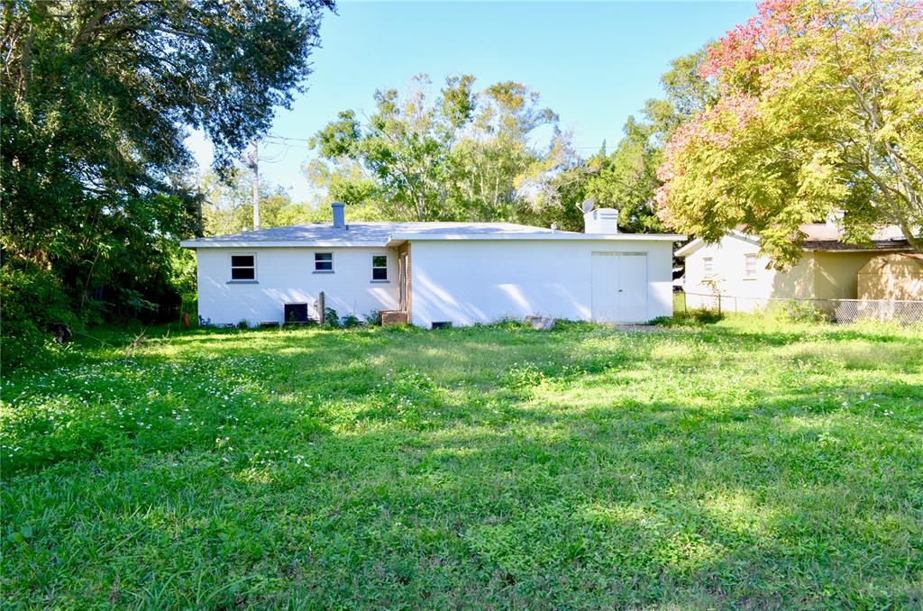 The rear exterior of a white, single-story house with a large, grassy backyard — 603 MARLENE DRIVE, DAYTONA BEACH, FL