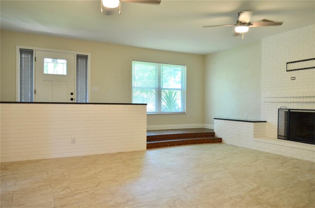 A living room features a white brick fireplace, a sunken floor area, and tile flooring — 603 MARLENE DRIVE, DAYTONA BEACH, FL