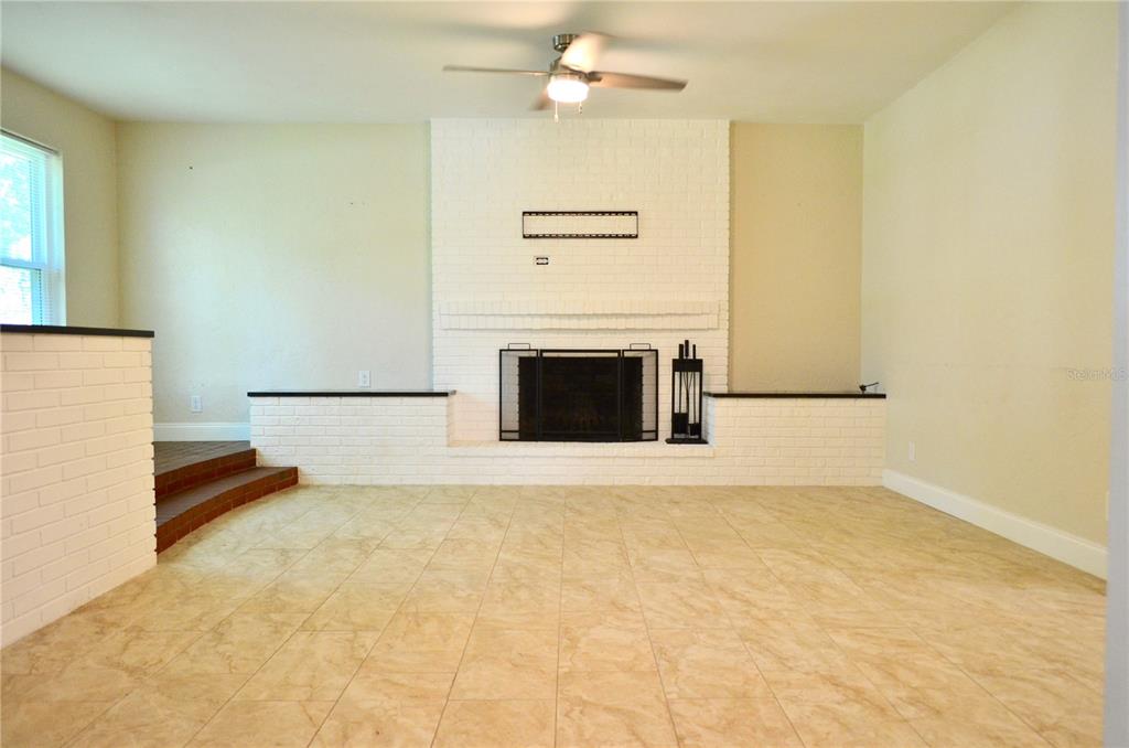 A living room features a white brick fireplace, tile flooring, and a ceiling fan — 603 MARLENE DRIVE, DAYTONA BEACH, FL