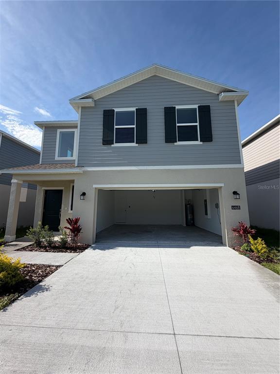 A two-story house features a light gray horizontal siding upper level, a stucco lower level, and an attached garage — 6468 DOMIZIO DRIVE, WINTER HAVEN, FL
