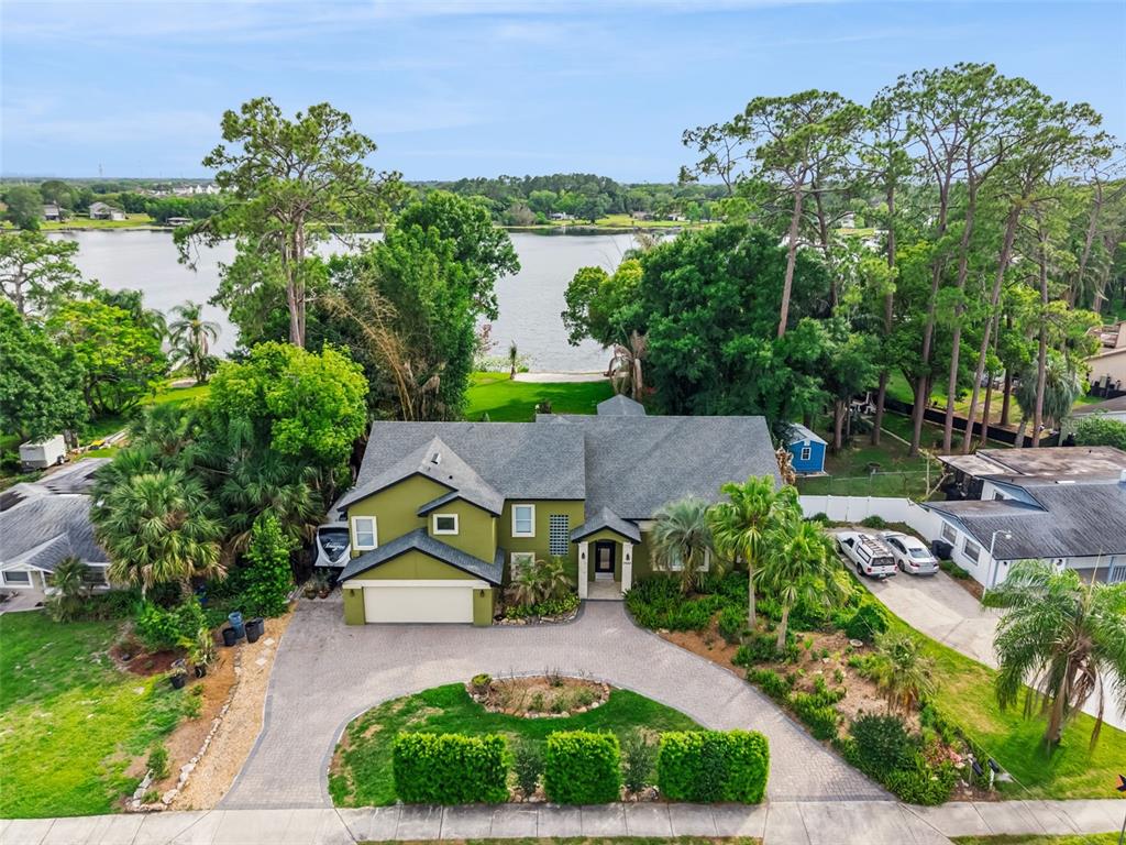 An aerial view shows a green two-story house with a circular driveway and lakefront backyard — 9642 BEAR LAKE ROAD, APOPKA, FL