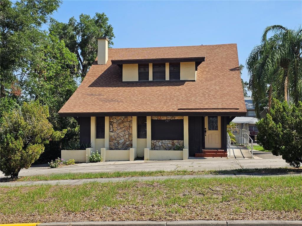 A two-story house features a stone facade, a brown shingled roof, and a front ramp — 737 W CENTRAL AVENUE, WINTER HAVEN, FL