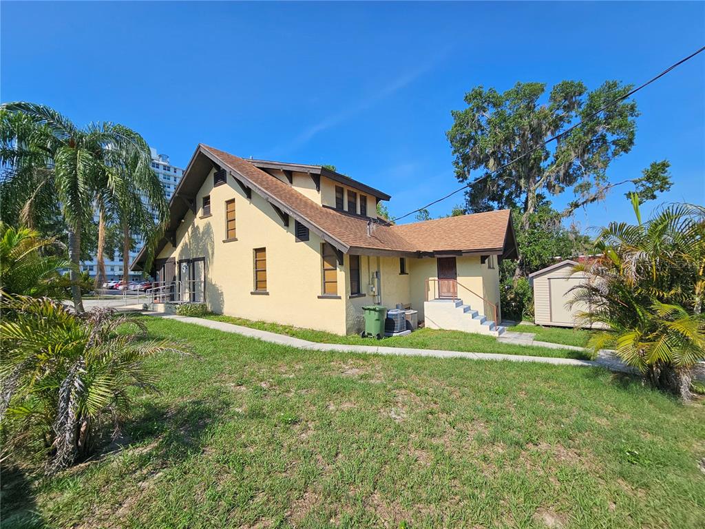A yellow house with a brown shingled roof sits on a grassy lot with palm trees — 737 W CENTRAL AVENUE, WINTER HAVEN, FL