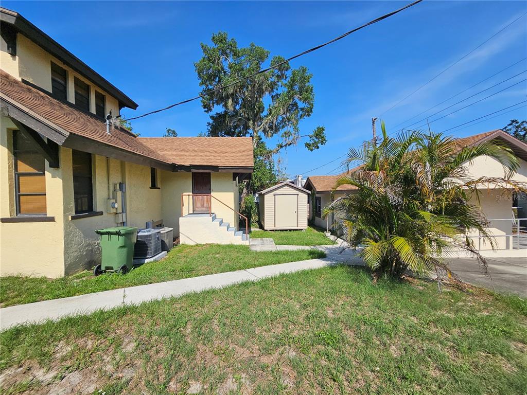The exterior view shows a yellow house with a shed, palm tree, and concrete walkway — 737 W CENTRAL AVENUE, WINTER HAVEN, FL
