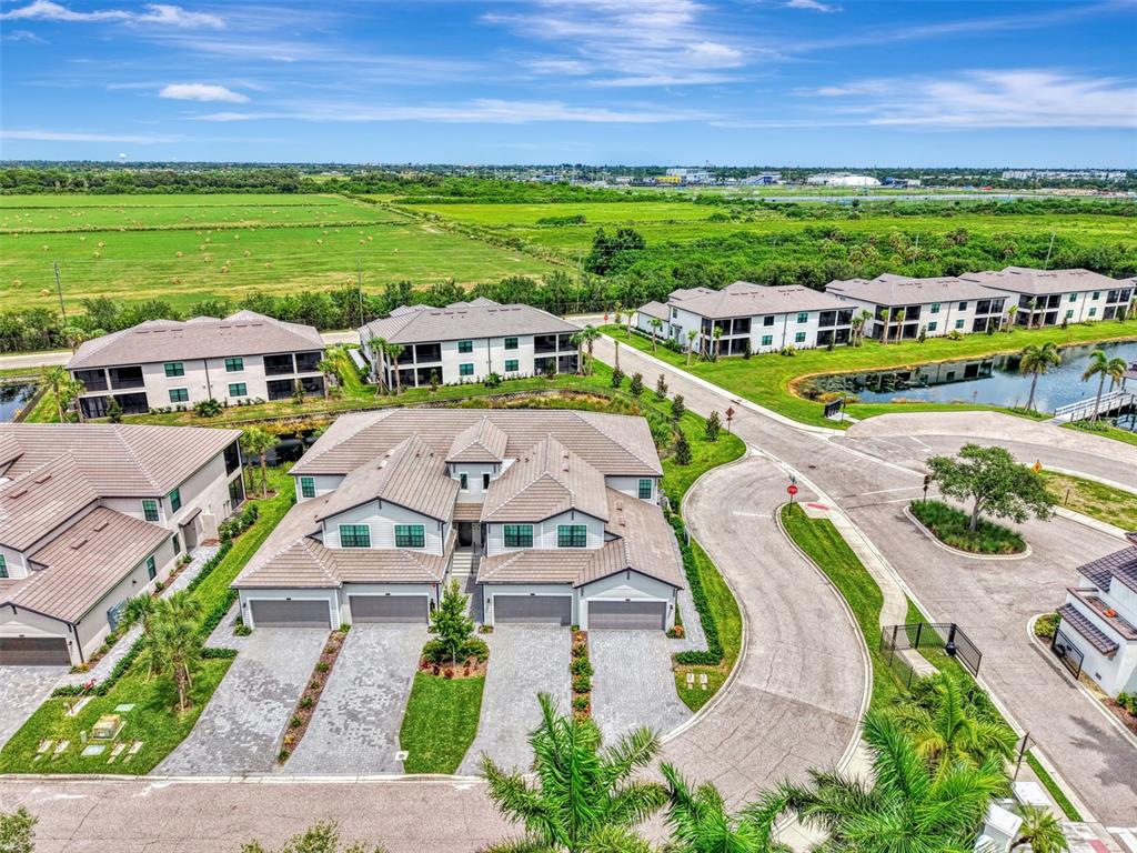 An aerial view shows a multi-unit residential building with gray roofs and paved driveways — 5632 SUMMIT POINTE CIRCLE UNIT 104, BRADENTON, FL