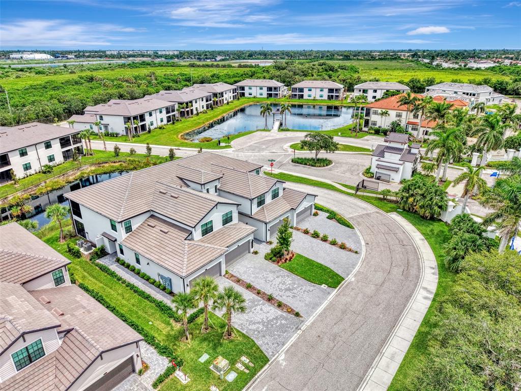 An aerial view shows multi-story residential buildings with tile roofs surrounding a central pond — 5632 SUMMIT POINTE CIRCLE UNIT 104, BRADENTON, FL