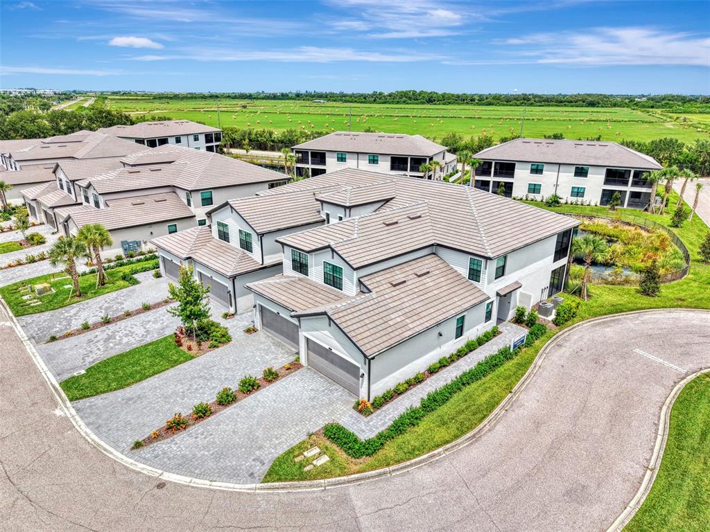 An aerial view shows several multi-story residential buildings with tiled roofs and paved driveways — 5632 SUMMIT POINTE CIRCLE UNIT 104, BRADENTON, FL