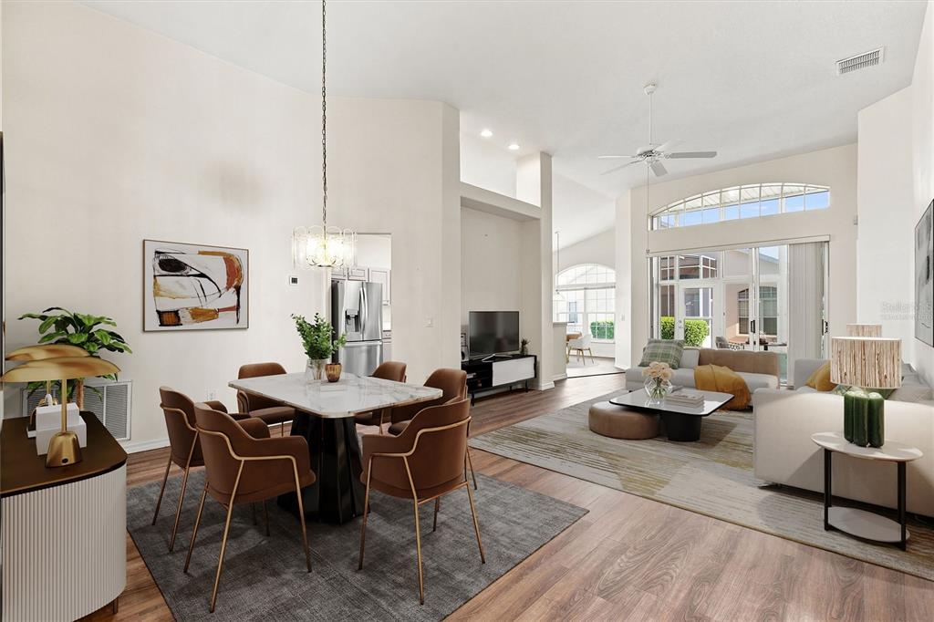 An open-concept living and dining area features vaulted ceilings, wood-look flooring, and large sliding doors — 238 FLEMING LN, DAVENPORT, FL