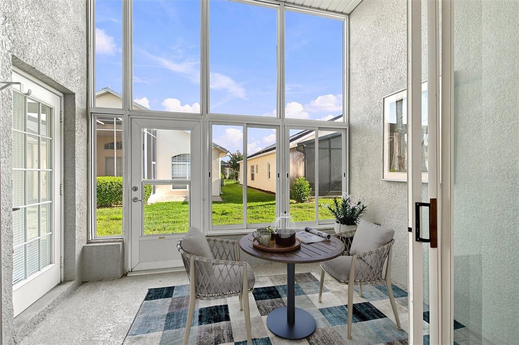 A sunroom features a small table with two chairs, a patterned rug, and large windows — 238 FLEMING LN, DAVENPORT, FL