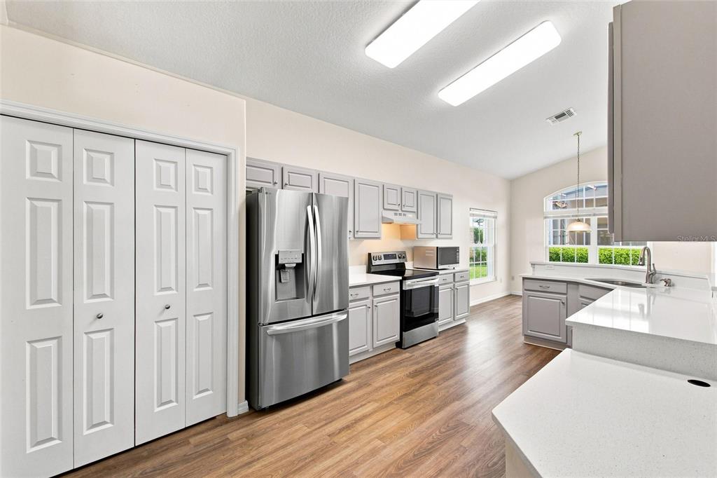 A kitchen with gray cabinets, stainless steel appliances, white countertops, and wood-look flooring — 238 FLEMING LN, DAVENPORT, FL