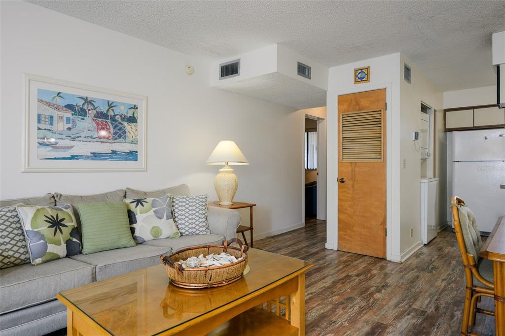 A living room features a gray sofa, a glass-topped coffee table, and wood-look flooring — 130 OCEAN HIBISCUS DRIVE UNIT 204, ST AUGUSTINE, FL