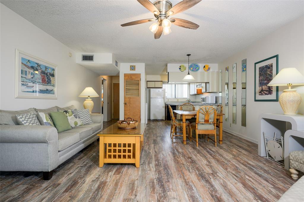 A living room and dining area feature wood-look flooring, a ceiling fan, and neutral walls — 130 OCEAN HIBISCUS DRIVE UNIT 204, ST AUGUSTINE, FL