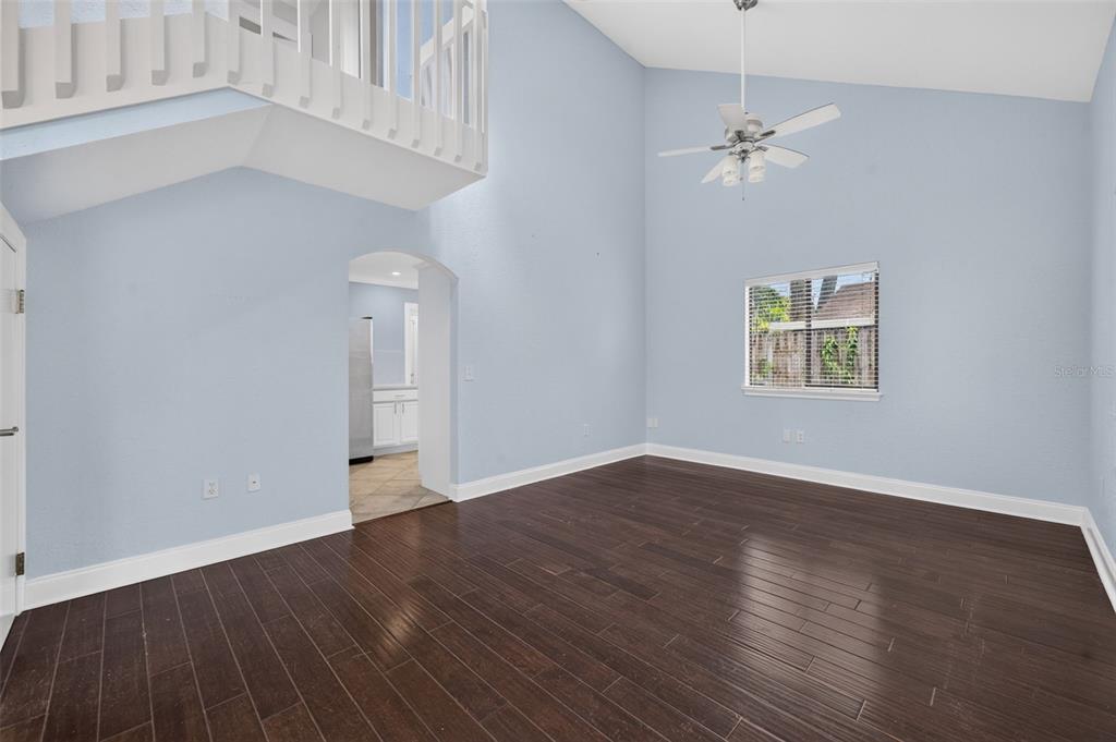 A living room features light blue walls, dark wood flooring, a vaulted ceiling, and a staircase — 1871 BRYAN AVENUE, WINTER PARK, FL