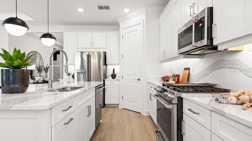 An open-concept living room and kitchen feature white cabinetry, modern lighting, and a pool view — 10610 ECLIPSE STREET, SARASOTA, FL