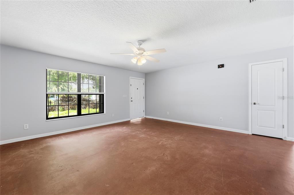 An empty room with light gray walls, a ceiling fan, and a stained concrete floor — 5377 BECK DRIVE, COCOA, FL