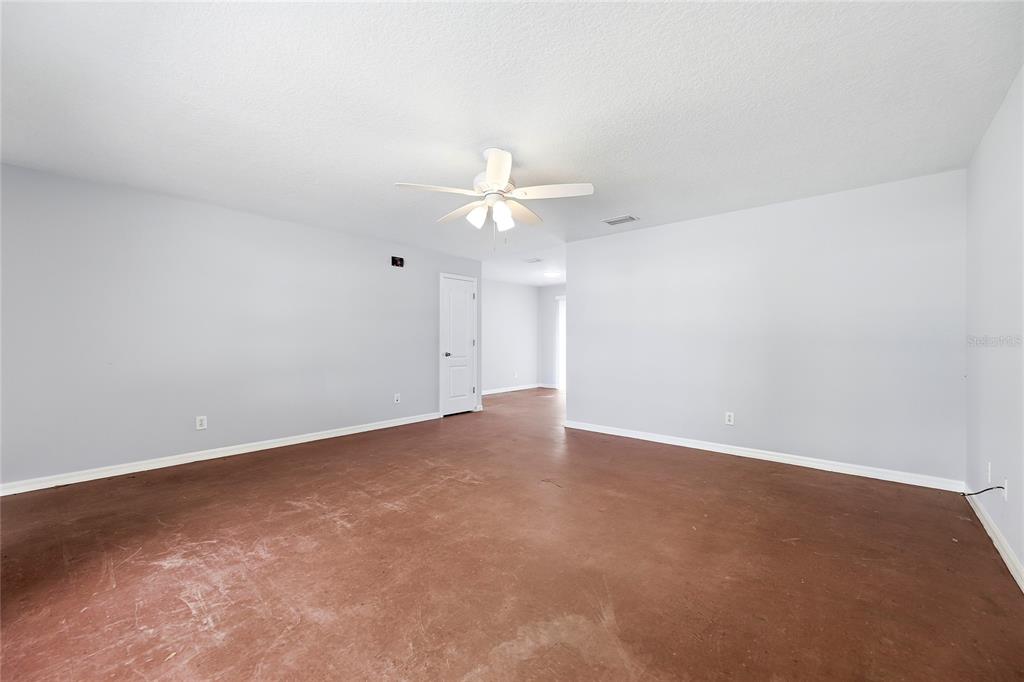 An empty room with light gray walls, a ceiling fan, and unfinished concrete flooring — 5377 BECK DRIVE, COCOA, FL