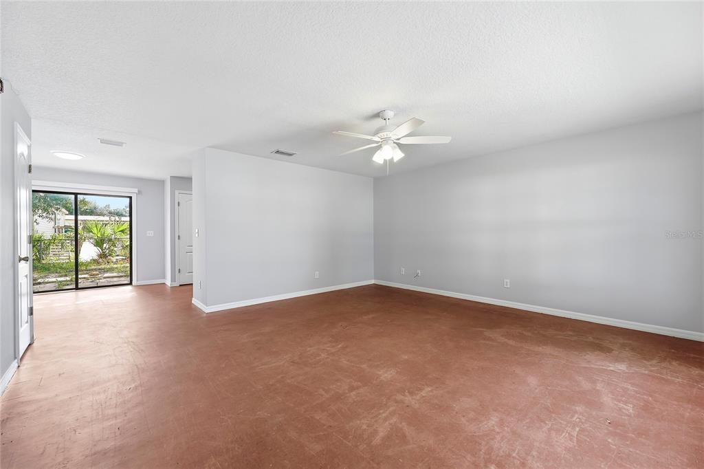 An empty room with light gray walls, a ceiling fan, and a reddish concrete floor — 5377 BECK DRIVE, COCOA, FL