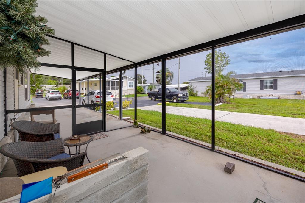 A light gray manufactured home features a large carport, a screened porch, and a concrete driveway — 6821 AMERICANA DRIVE NE UNIT 106, ST PETERSBURG, FL