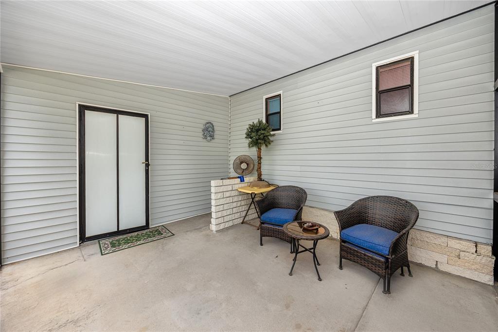 A light-colored mobile home features a screened-in porch and a concrete driveway — 6821 AMERICANA DRIVE NE UNIT 106, ST PETERSBURG, FL