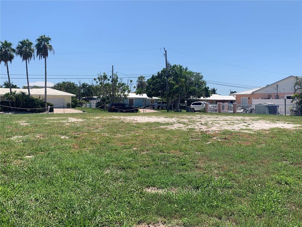 A vacant, grassy lot with palm trees and houses in the background under a blue sky — 538 67TH STREET, HOLMES BEACH, FL