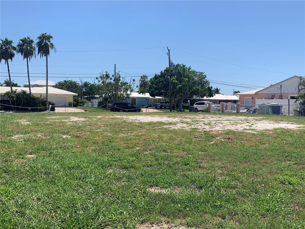 A vacant, grassy residential lot with scattered palm trees and surrounding houses in the background — 538 67TH STREET, HOLMES BEACH, FL