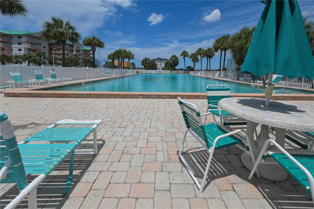 A swimming pool surrounded by a brick patio, lounge chairs, and palm trees — 18399 GULF BOULEVARD UNIT 367, INDIAN SHORES, FL