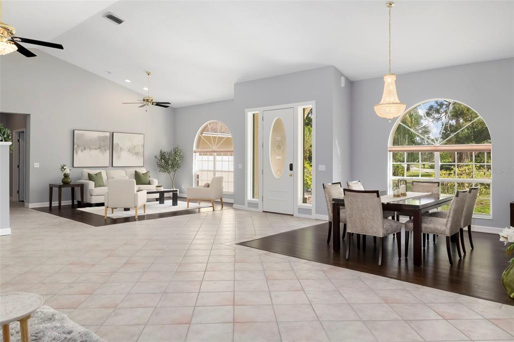A bright, open-concept living and dining area features tile flooring, dark wood accents, and arched windows — 296 PINE RANCH TRAIL, OSPREY, FL