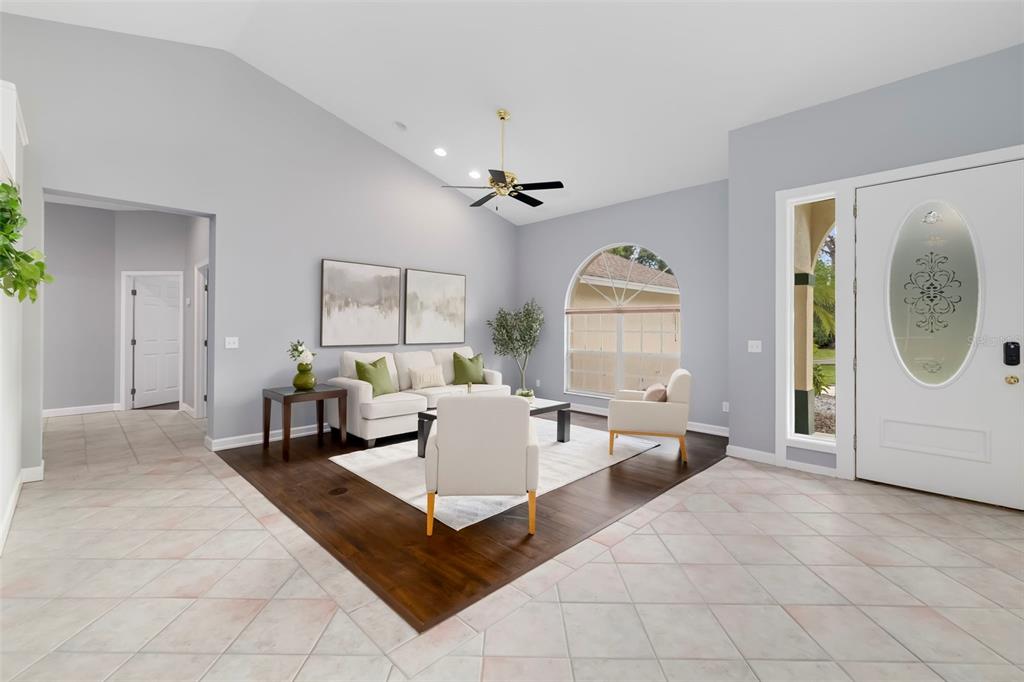 A living room features a vaulted ceiling, tile flooring, and a central wood-floored seating area — 296 PINE RANCH TRAIL, OSPREY, FL