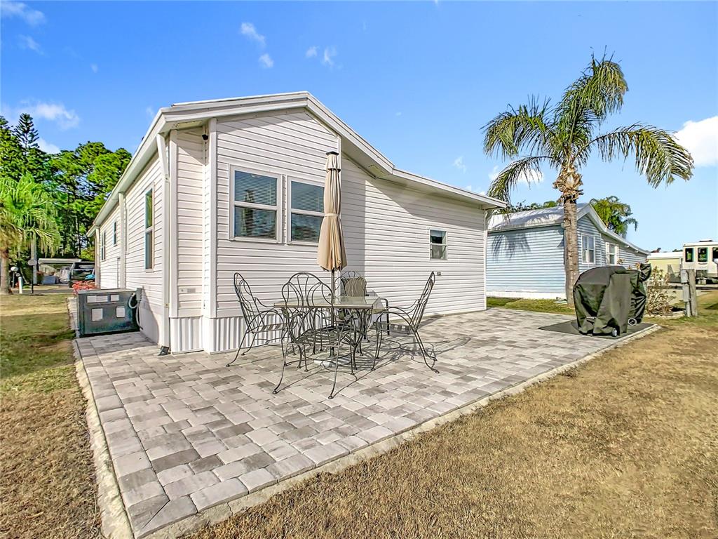 A white mobile home features a paved patio with a dining set and a grill — 446 PINE LOOP, FROSTPROOF, FL