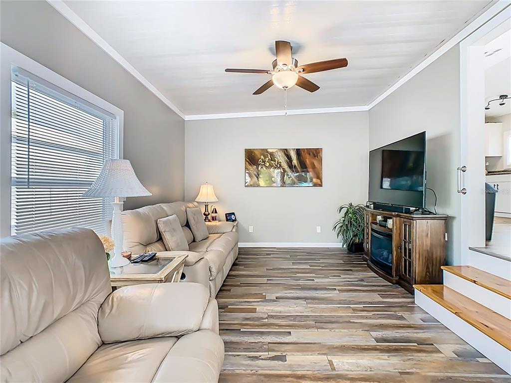 A living room features light-colored leather sofas, a television on a wooden console, and wood-look flooring — 446 PINE LOOP, FROSTPROOF, FL