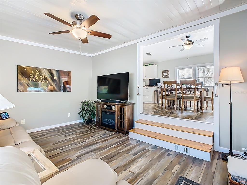 A living room with wood-look flooring leads up two steps to a dining area — 446 PINE LOOP, FROSTPROOF, FL