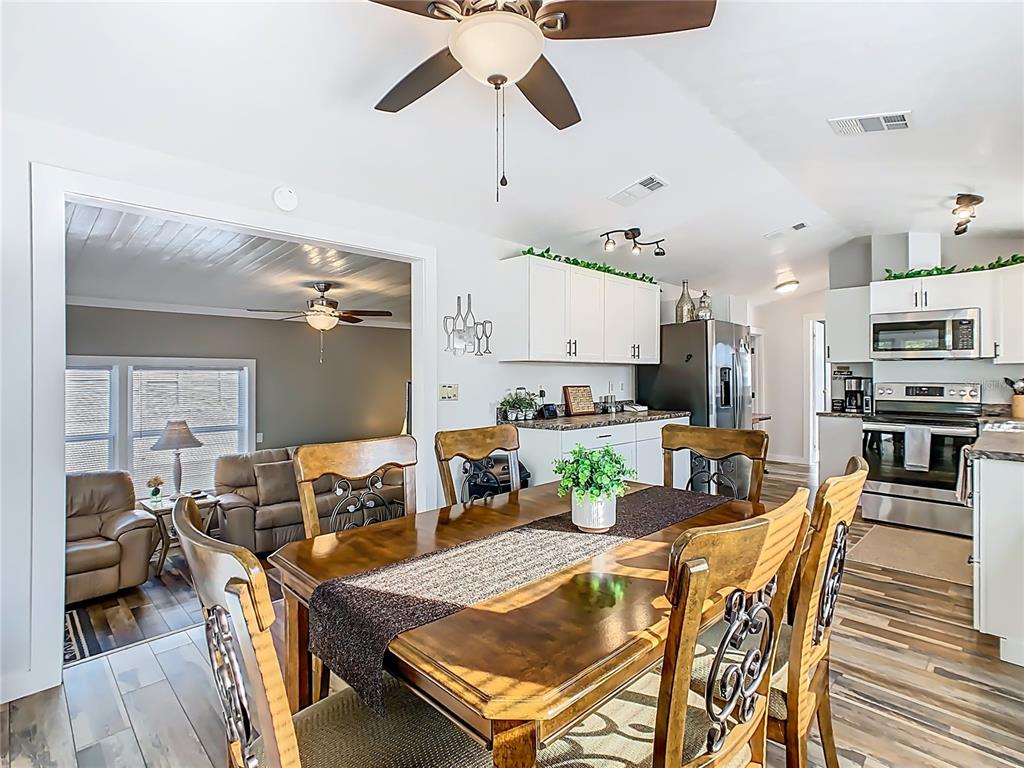 A dining area with a wooden table and chairs opens into a kitchen and living room — 446 PINE LOOP, FROSTPROOF, FL