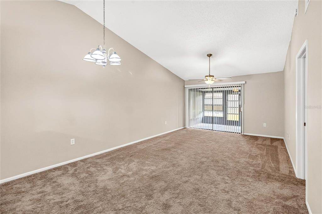 A living room with beige carpet, a light-colored sofa, and an adjacent dining area — 2791 KING OAK CIRCLE, ST CLOUD, FL