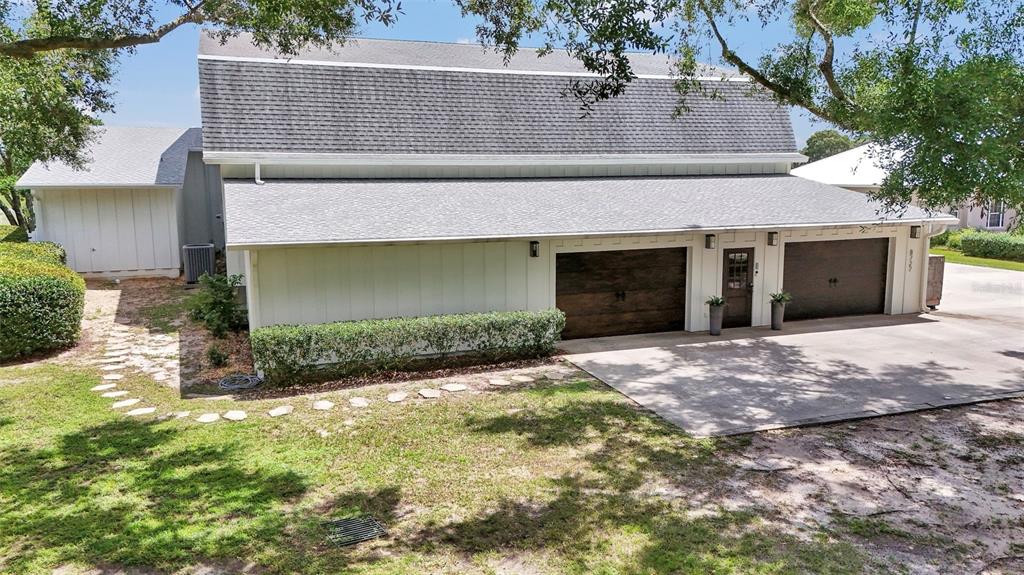An exterior view of a white barn-style building with two dark wood garage doors — 8727 SE 72ND AVENUE, OCALA, FL