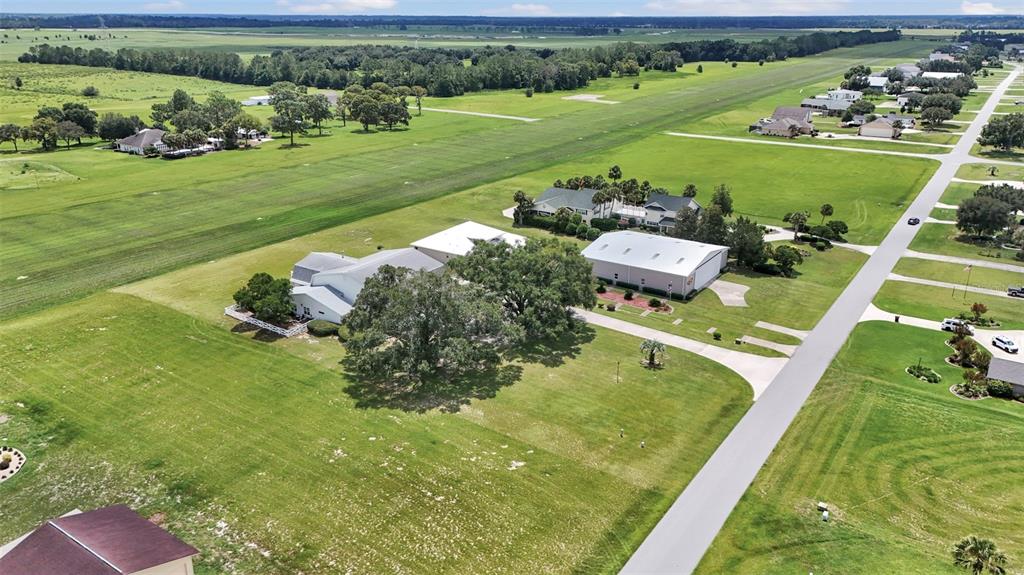An aerial view shows a residential property with a large hangar next to a runway — 8727 SE 72ND AVENUE, OCALA, FL