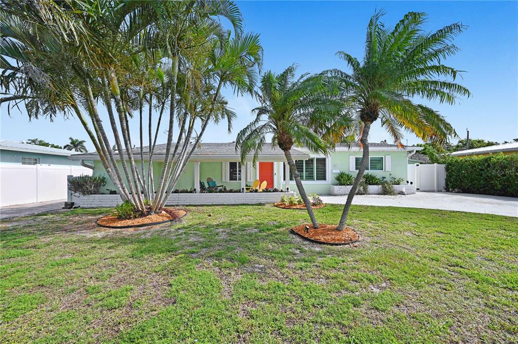 A single-story house with a light green exterior, orange front door, and palm trees — 231 OCEAN BOULEVARD, SATELLITE BEACH, FL