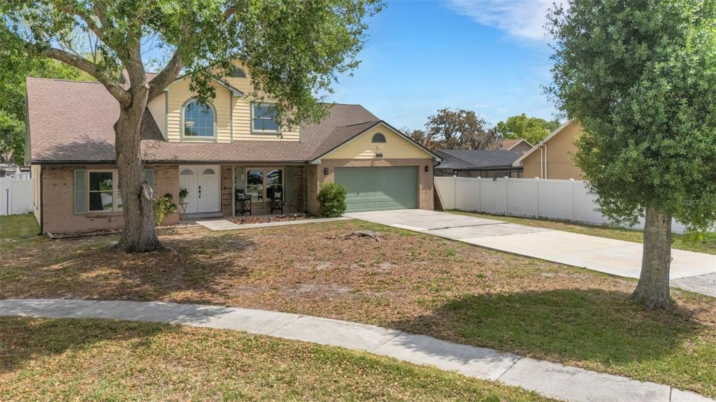 A two-story house with a brick facade, yellow siding, and a green garage door — 4304 LUKOW PLACE, VALRICO, FL