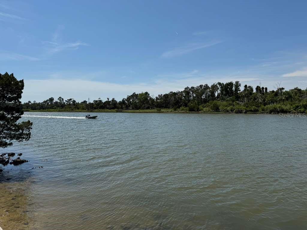 A small motorboat travels across a wide river with a treelined shore in the background — 7801 N WANDA POINT, CITRUS SPRINGS, FL