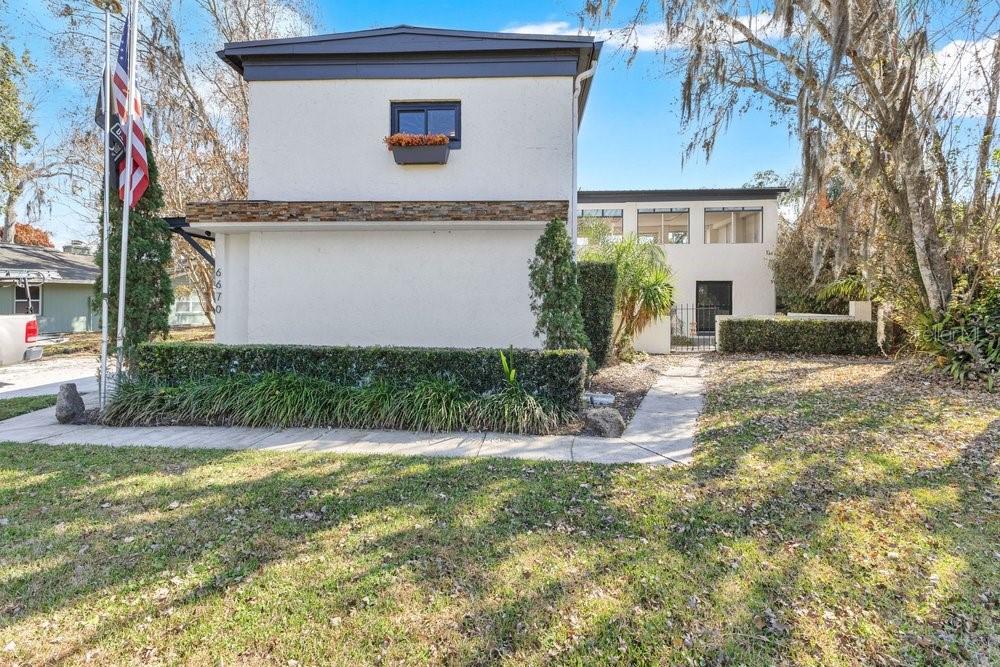 A two-story house with white stucco walls, a stone accent band, and a flag pole — 6670 BAY SHORE DRIVE, ST CLOUD, FL