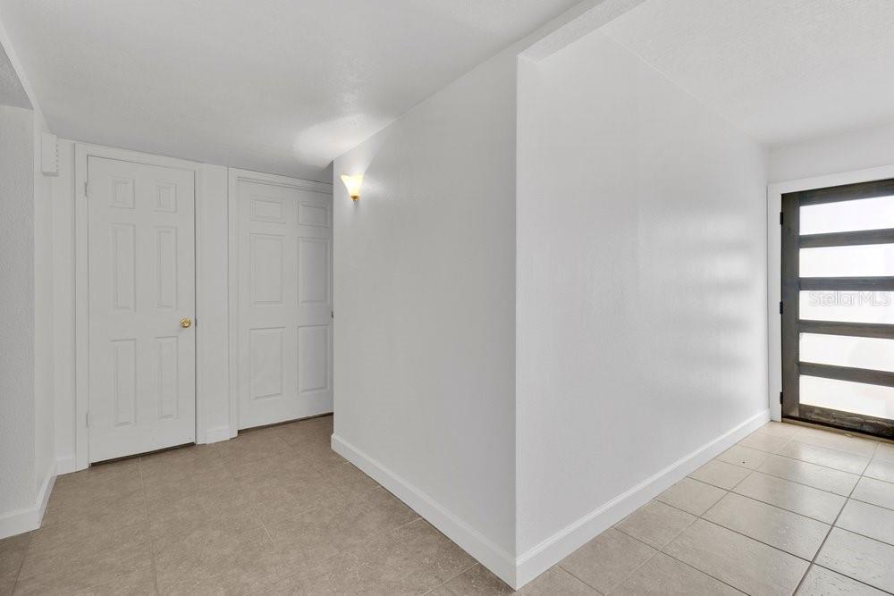 An entryway with white walls, tile flooring, two closed doors, and a glass-paneled front door — 6670 BAY SHORE DRIVE, ST CLOUD, FL