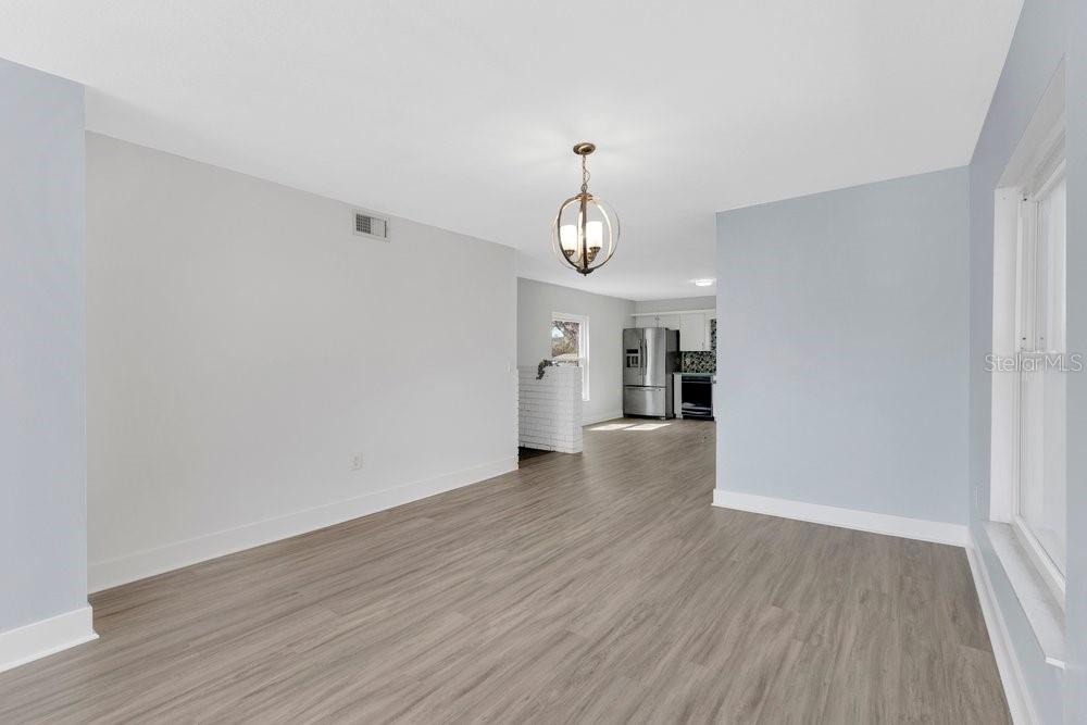 A dining area with light wood-look flooring leads into a kitchen with stainless steel appliances — 6670 BAY SHORE DRIVE, ST CLOUD, FL