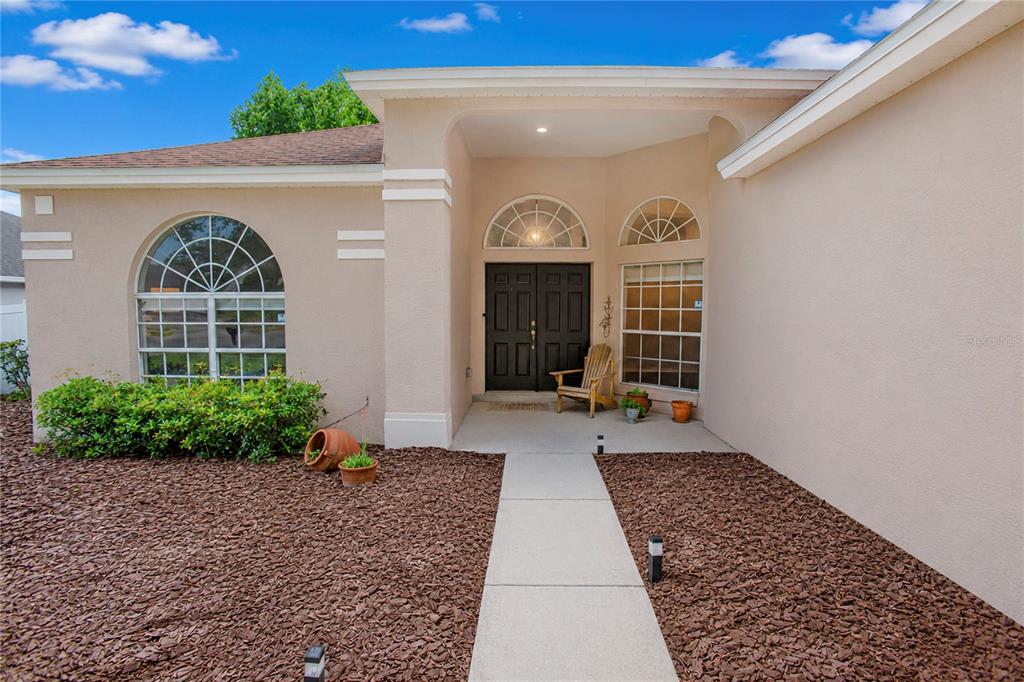 The exterior of a tan house features a concrete walkway leading to a double door — 3307 ROYAL ASCOT RUN, GOTHA, FL