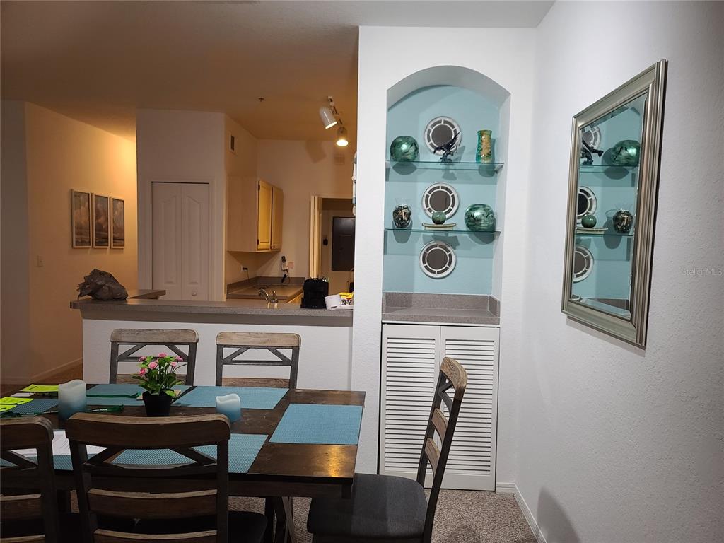 A dining area features a wooden table, chairs, and a built-in arched display niche — 8908 LEGACY COURT UNIT 16-104, KISSIMMEE, FL