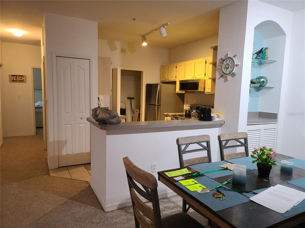 A kitchen with light cabinets and a breakfast bar overlooks a dining area with chairs — 8908 LEGACY COURT UNIT 16-104, KISSIMMEE, FL