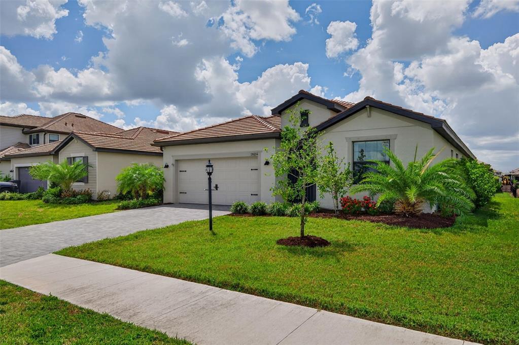 A single-story house with a two-car garage, tile roof, and landscaped front yard — 15126 MISTY WATER CROSSING, BRADENTON, FL