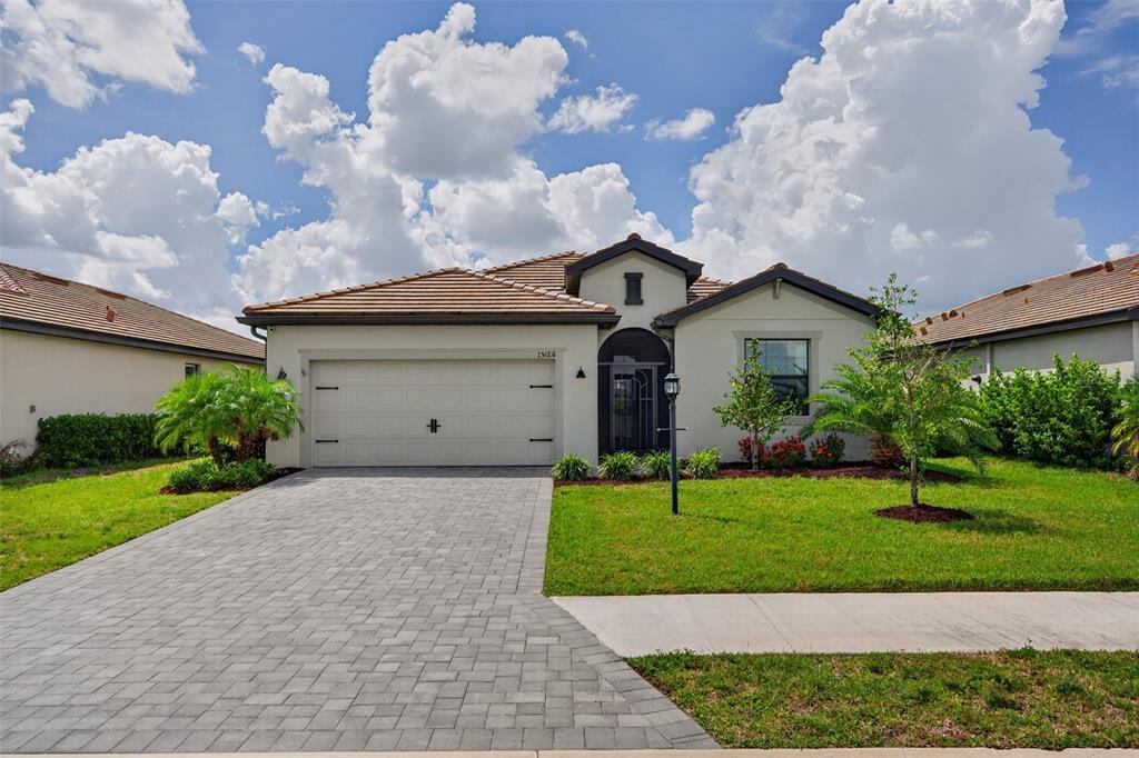 A single-story house with a paved driveway, two-car garage, and a tiled roof — 15126 MISTY WATER CROSSING, BRADENTON, FL