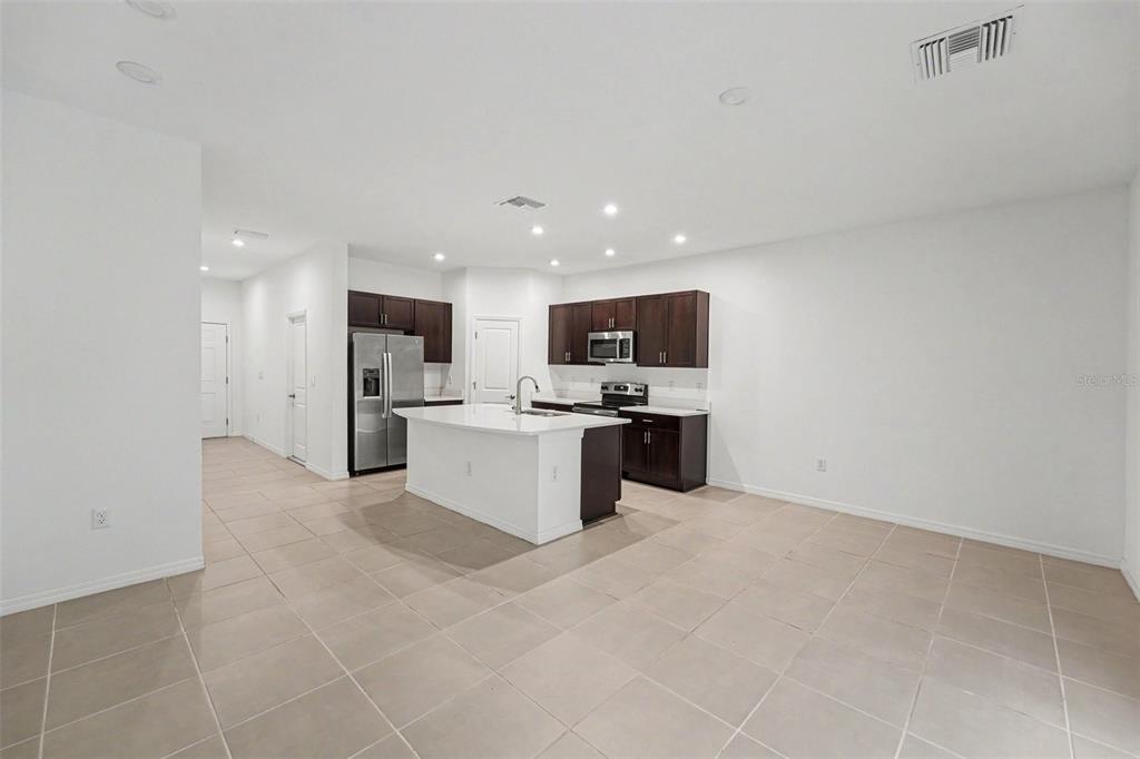 A kitchen features dark wood cabinets, a white island, and light tile flooring — 10573 OAKSIDE DRIVE, PALMETTO, FL