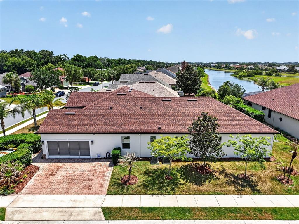 An aerial view shows a single-story house with a brown shingled roof and a driveway — 8237 BRIDGEPORT BAY CIRCLE, MOUNT DORA, FL
