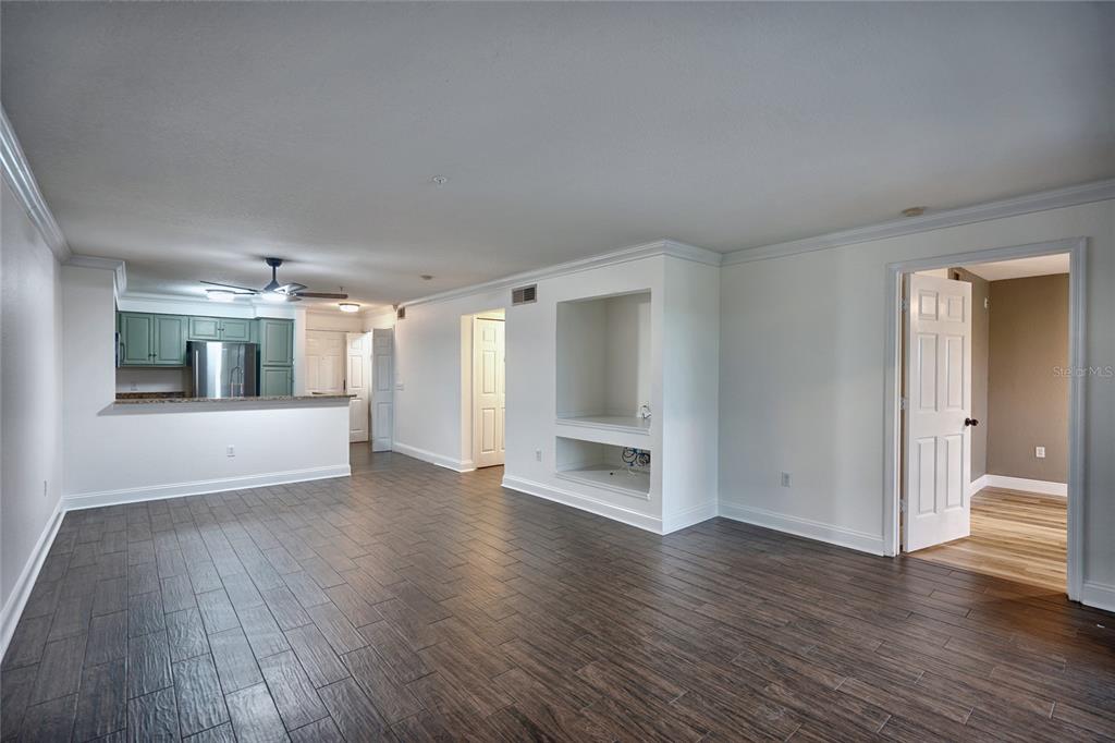 An open living area features dark wood-look tile flooring, white walls, and a built-in niche — 13815 FAIRWAY ISLAND DRIVE UNIT 1335, ORLANDO, FL